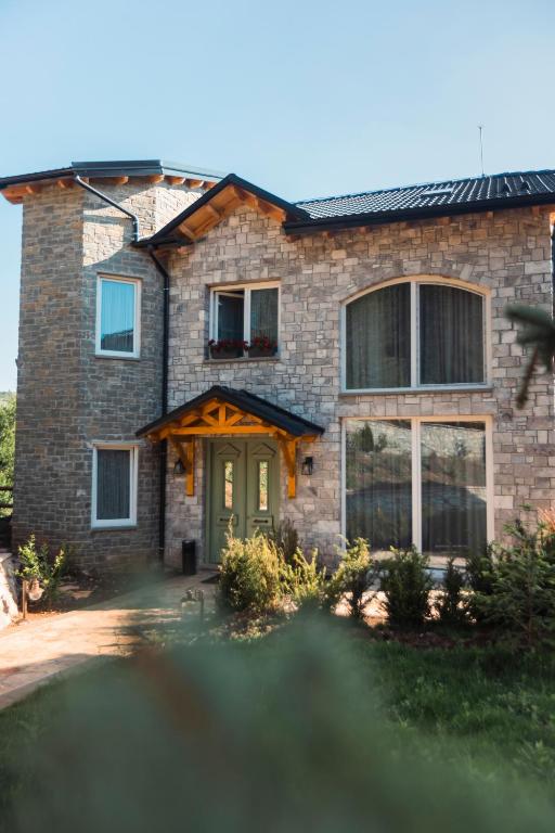 a brick house with a green door at Ura e Kovacit Resort & Agrotourism in Voskopojë