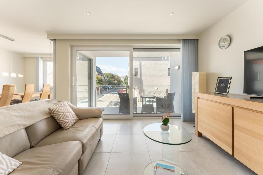 ein Wohnzimmer mit einer Couch und einem Glastisch in der Unterkunft Apartment La Dune Blanche - Ontspannen in Bredene in Bredene