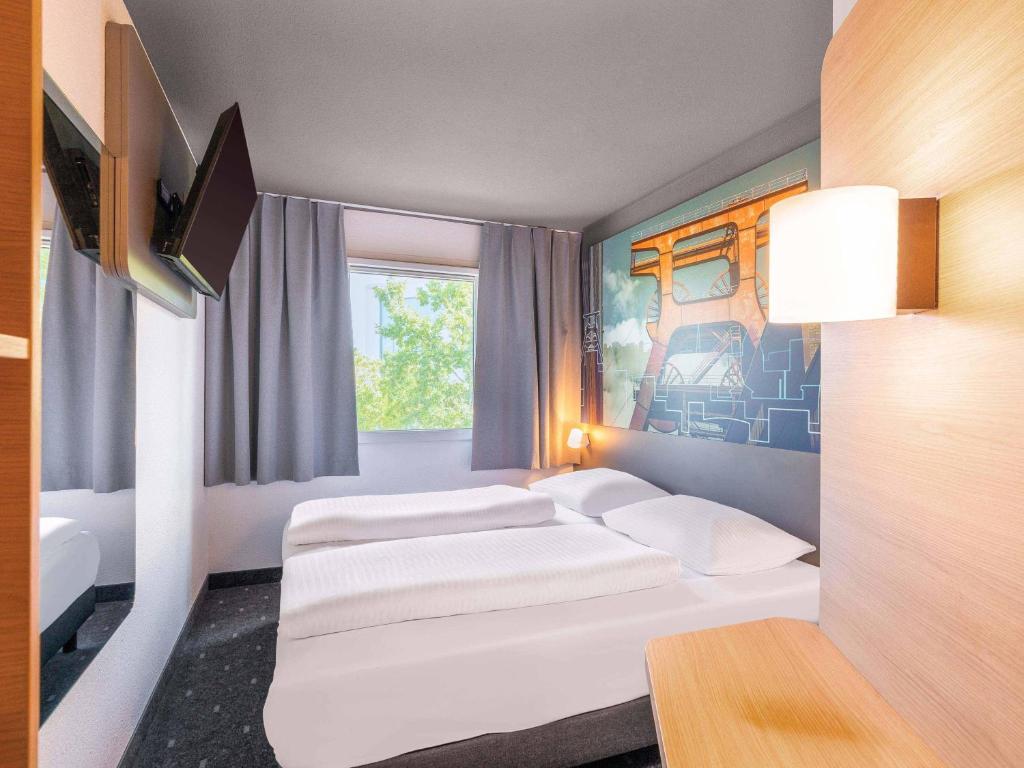 a hotel room with two beds and a window at B&B HOTEL Würzburg-Ost in Würzburg
