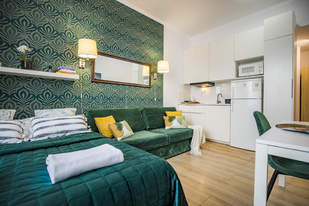 a living room with a green couch and a kitchen at MGR MiniStudio Bitwy Warszawskiej obok Lotnisko Warszawa in Warsaw