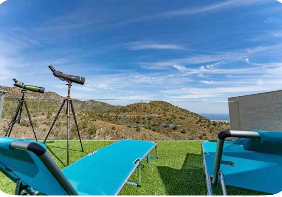 Un telescopio y una mesa con vista al océano. en El Mirador de Carmina Habitaciones, en Frigiliana
