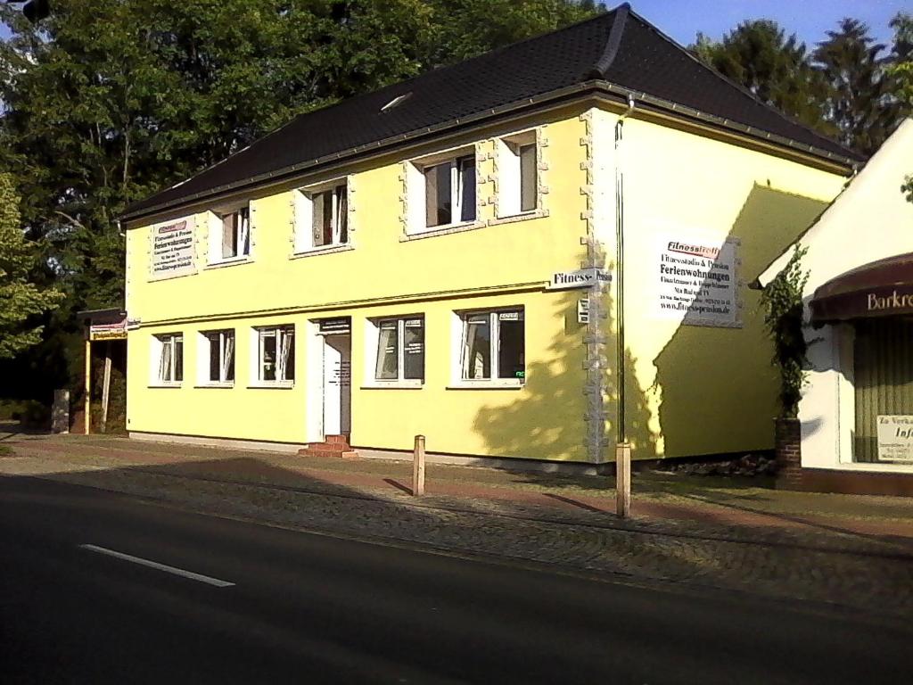 een geel en wit gebouw aan de straatkant bij Fitness Pension in Sulingen