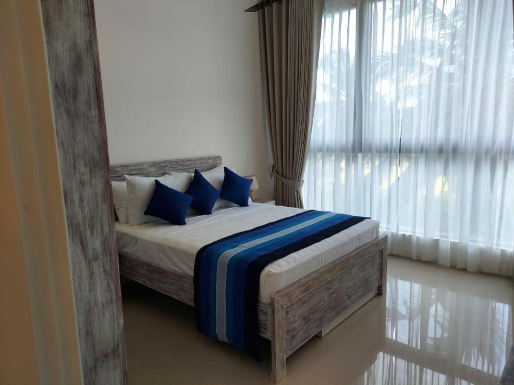 a bedroom with a bed with blue pillows and a window at Sea & Turtles Galle condo in Galle