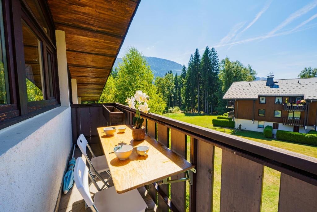a table on a balcony with a view of a house at L'Envol de Praz - Proche pistes et base de loisirs in Praz-sur-Arly