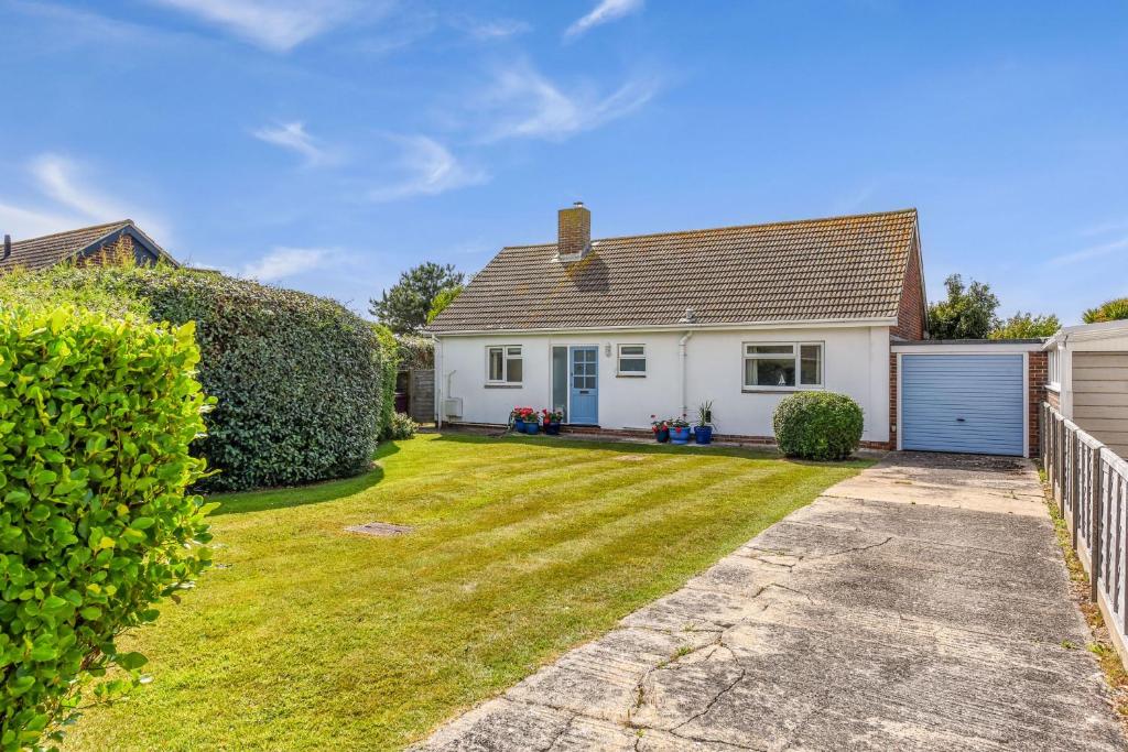 a white house with a yard at 21 Owers Way, West Wittering in West Wittering