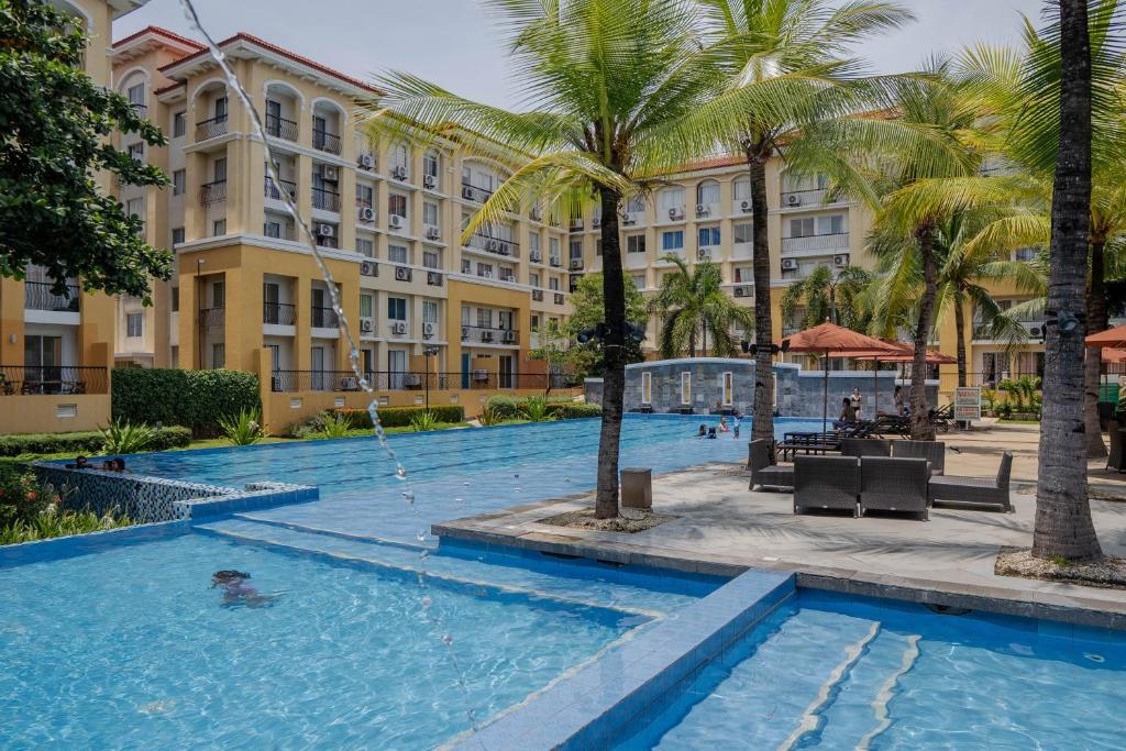 a swimming pool in front of a hotel with palm trees at San Remo Oasis City Di Mare Condo Unit 6118 in Cebu City