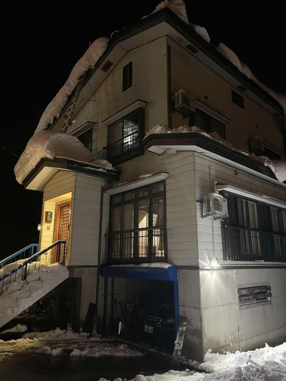 a house with snow on the side of it at night at E KI house ski school in Yuzawa