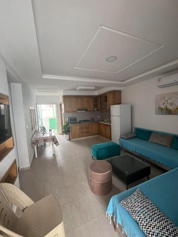 a living room with a blue couch and a kitchen at Dar ATTIA Ezzahra KELIBIA in Ḩammām al Ghazzāz