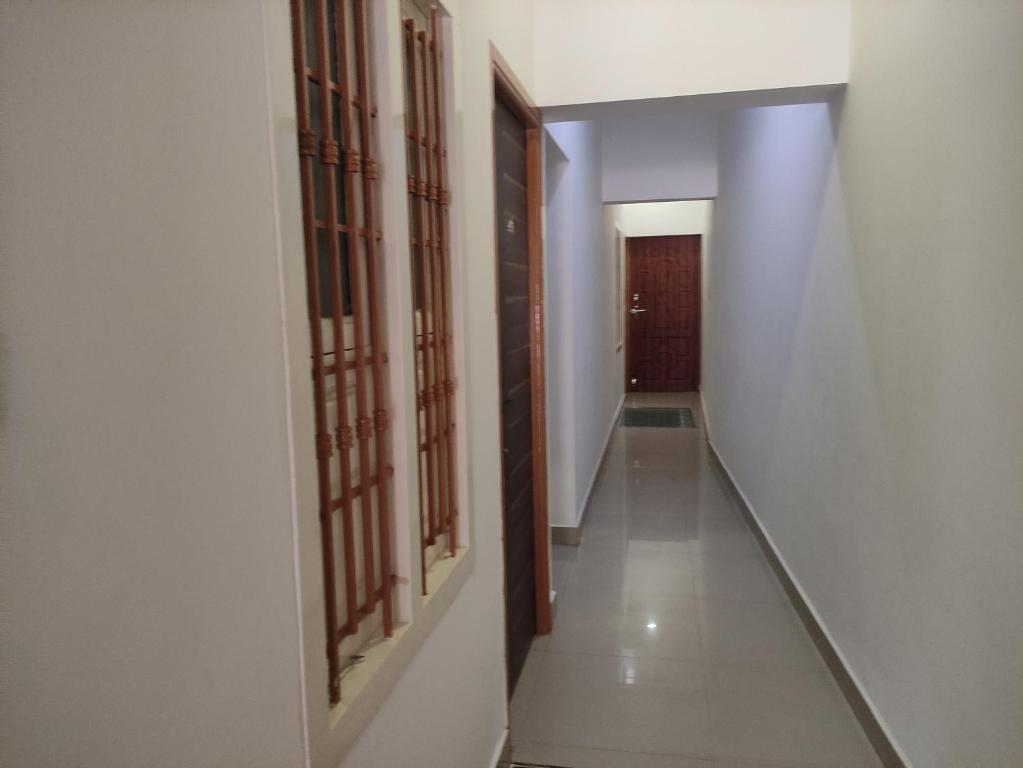 a hallway with white walls and wooden doors at Temple opposite Rooms in Tiruvannāmalai
