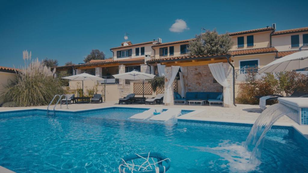 a swimming pool with a fountain in front of a house at Villa Kalista Istriana in Mednjan