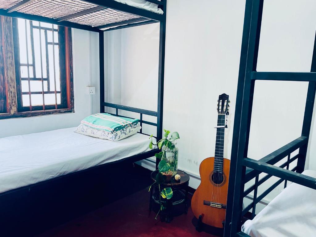 a room with a bed and a guitar in it at Ku'Vana Hostel Kandy in Kandy