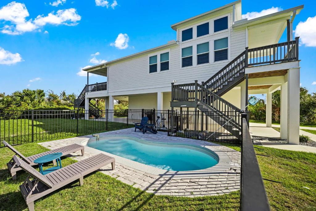 a house with a swimming pool with a staircase and two benches at Luxury Beach Home with Heated Pool in Marineland