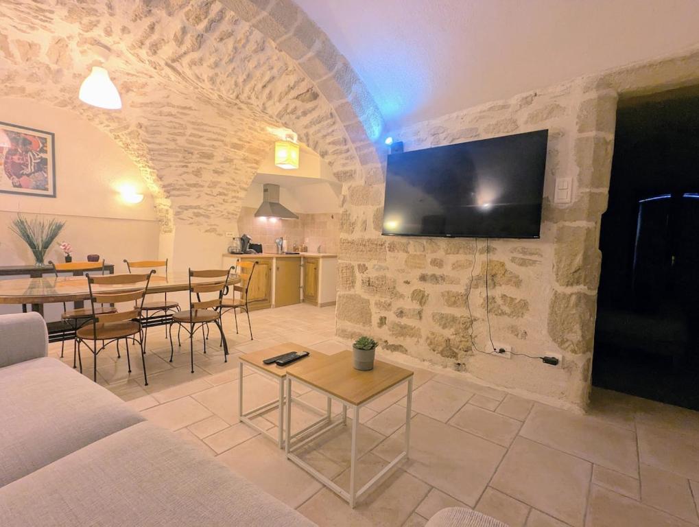 un salon avec un canapé et une télévision sur un mur dans l'établissement Le Mistral - Pont du Gard - Cozy & Intime - WiFi fibre -TV, à Saint-Bonnet-du-Gard