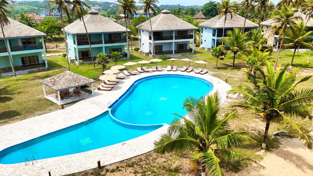 an aerial view of a resort with a pool and palm trees at AnoMansa Beach Resort at Elmina Bay in Elmina
