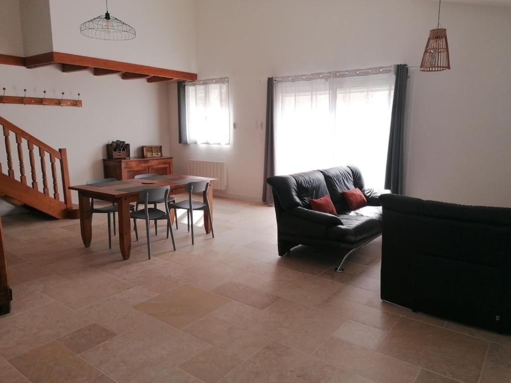 ein Wohnzimmer mit einem Tisch und einem Sofa in der Unterkunft Maison de 80m2 avec cour fermée et sécurisée in Crozes-Hermitage
