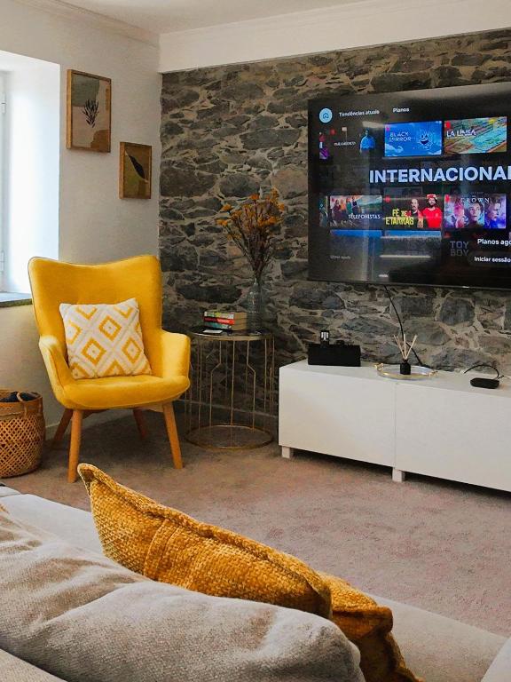 a living room with a yellow chair and a tv at RETIRO Da CALHETA in Estreito da Calheta