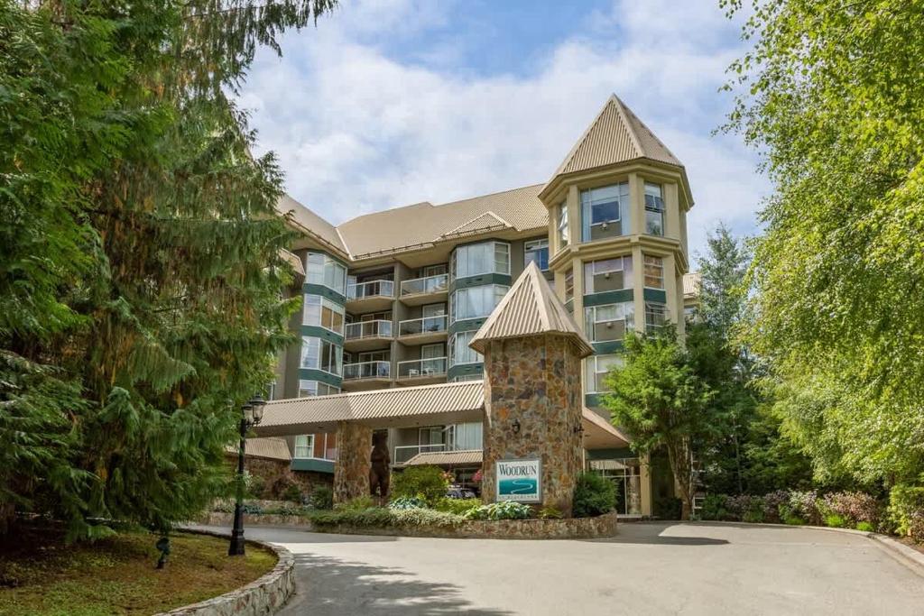 a large apartment building with a tower at Woodrun Lodge 414 | Cozy Ski-In Ski-Out Condo w/ Shared Hot Tub, Pool, Fireplace, & Parking in Whistler