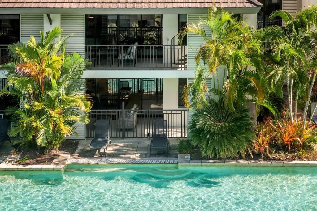 a house with a swimming pool and palm trees at Infinity's Edge - Poolside Retreat at Temple Resort in Craiglie