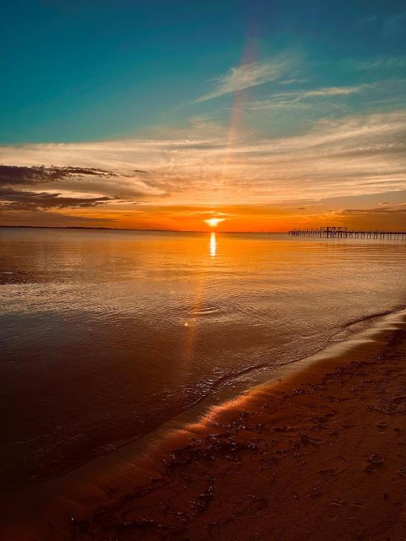 a sunset over the ocean with a pier in the background at Windmark-Beach Therapy in Port Saint Joe