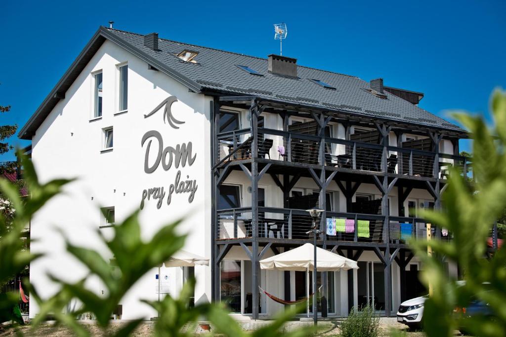 a white building with a sign on it at Dom Przy Plaży w Dąbkach in Dąbki