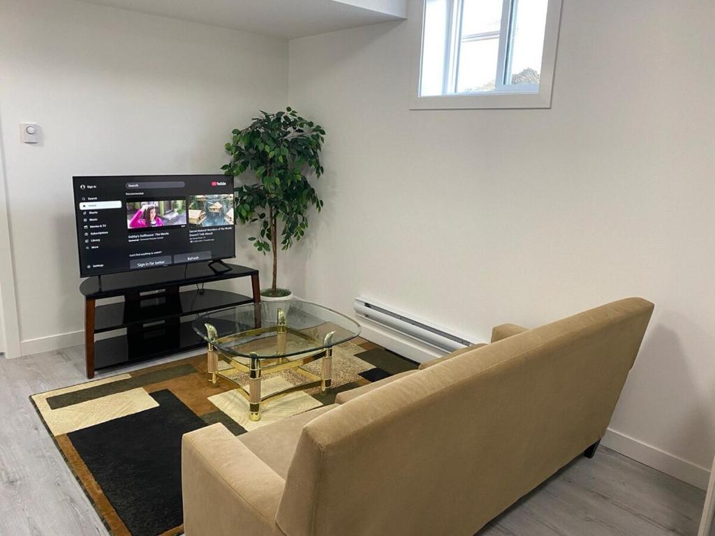 a living room with a couch and a tv at Cozy 2-Bedroom Suite in Aspen Ridge in Saskatoon
