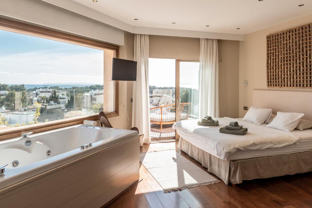 a bedroom with a tub and a bed and a window at Luxury Villa With Pool And Seaview in Nuestra Señora de Jesus