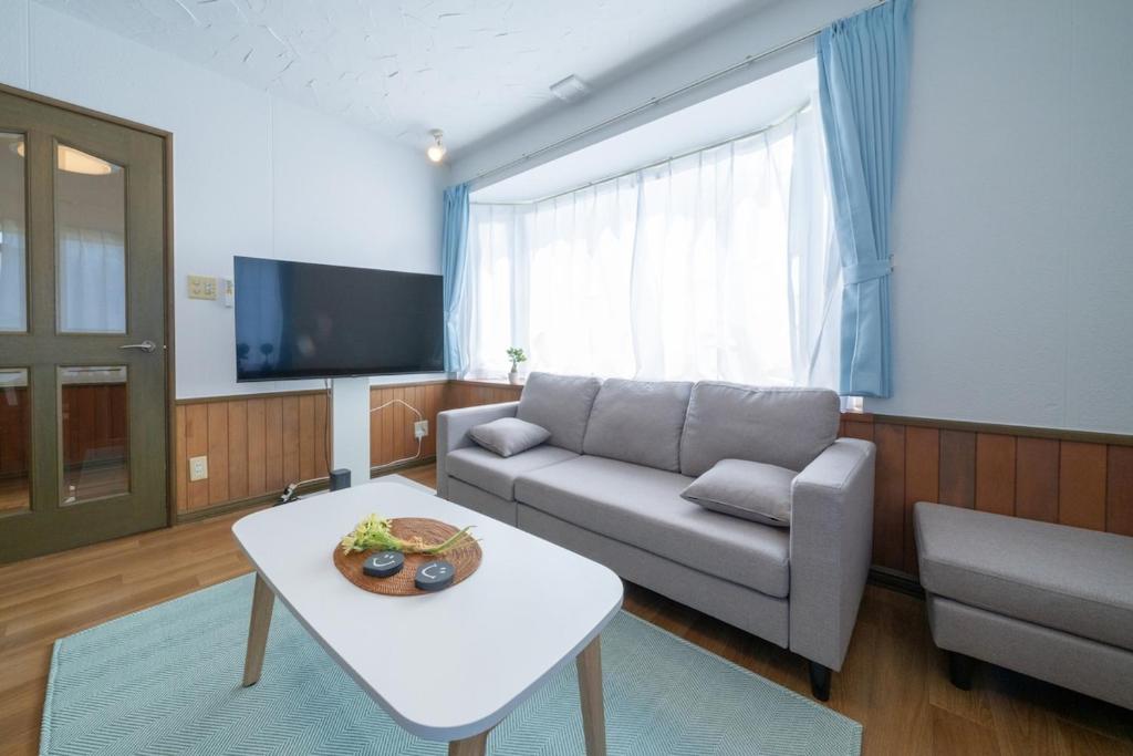 a living room with a couch and a table at Asahikawa House 1F in Asahikawa