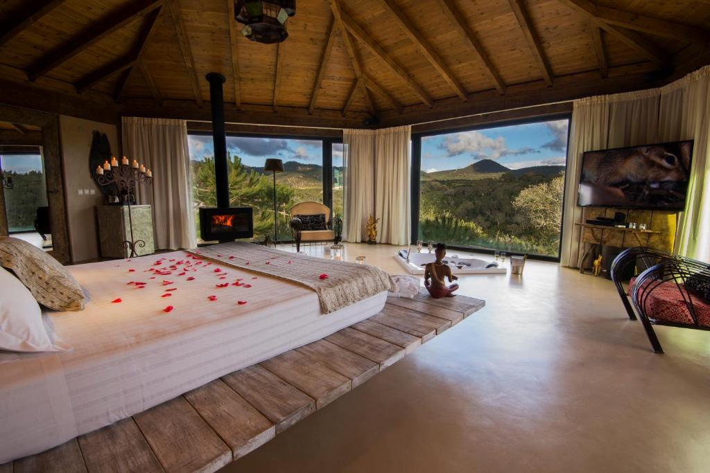 ヴィラ・ノヴァ・デ・ミルフォンテスにあるHerdade do Amarelo Nature & Spaのベッドルーム1室(赤いバラの花びらが描かれた大型ベッド1台付)