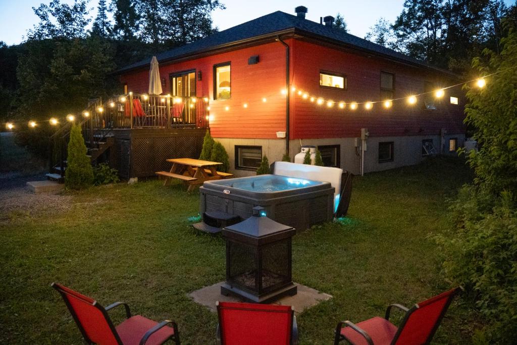 a house with a hot tub in the yard at Chalet des Érables in Petite-Rivière-Saint-François