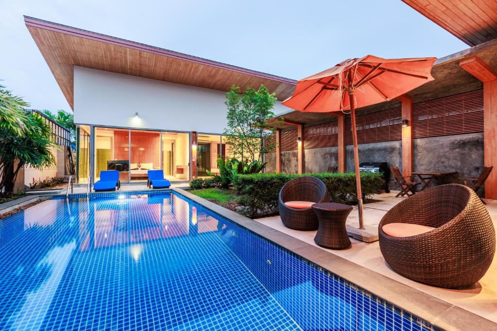 a swimming pool with chairs and an umbrella at Villa Coco - Classy Modern 2 Bedroom Pool Villa in Ban Saiyuan (1)