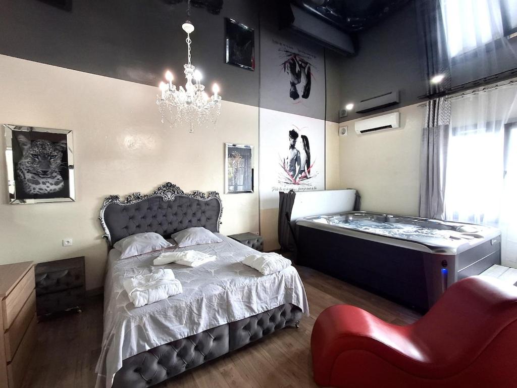una camera da letto con un letto e un lampadario di La discrète romantique, appartement avec jacuzzi a Charavines