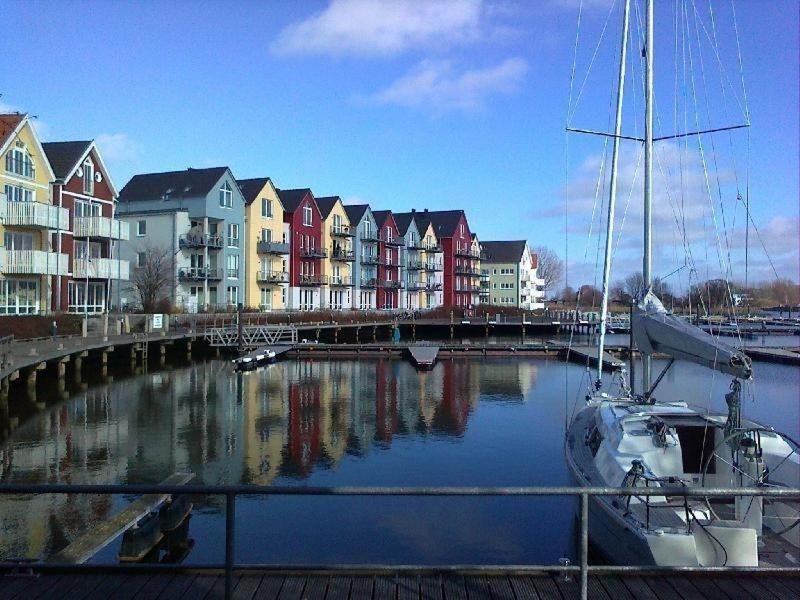a boat is docked in a marina with houses at Design Appartment Picasso am Yachthafen Greifswald in Greifswald