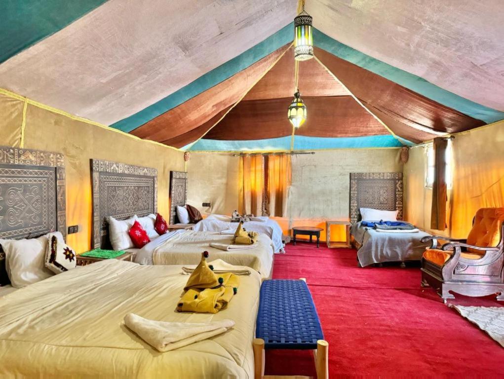 メルズーガにあるErg Chabbi Luxury Campのベッド4台とテントのある寝室