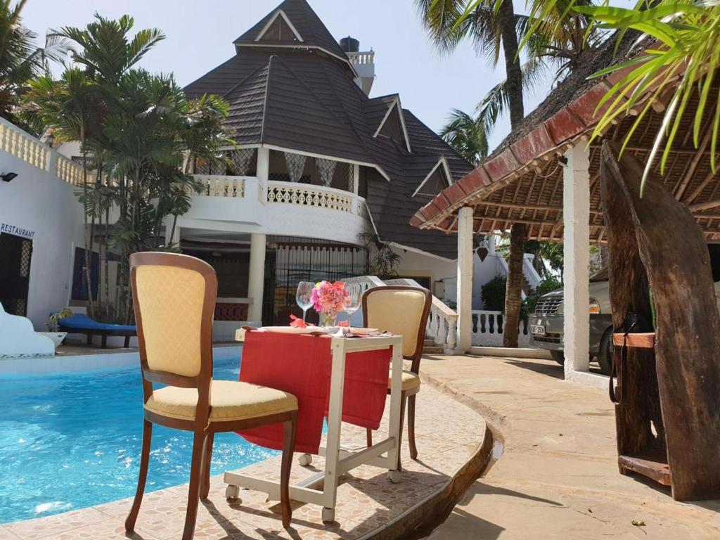 a table and chairs next to a pool at Cozy Beachside Retreat in Diani Kwale County in Galu