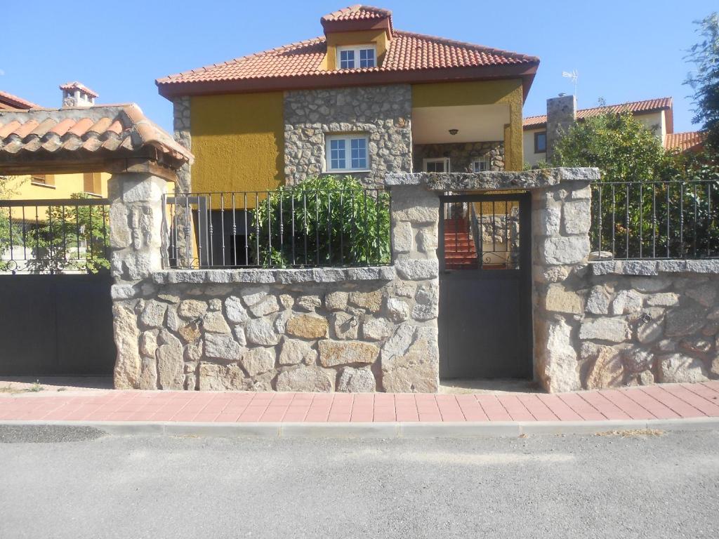 a house with a stone wall and a gate at En casa de Carlos in Ortigosa del Monte