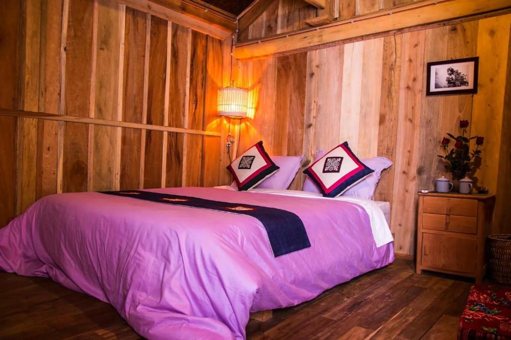 a bedroom with a bed with pink sheets and a lamp at Mèo Vạc Giấc Xưa Homestay in Mèo Vạc
