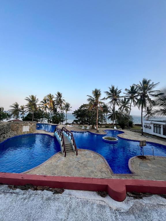 a large swimming pool with palm trees in the background at Coastal bliss apartment in Mombasa