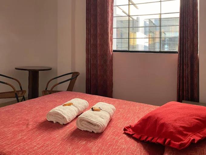 two towels on a red bed with a window at Hotel Marabi in Quillabamba