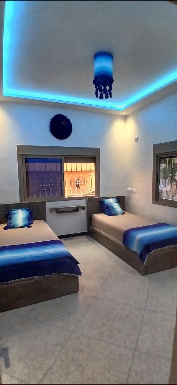 AfourerLH Appart 1 très bel appartement avec vue sur les montagnes的蓝色灯的客房内的两张床