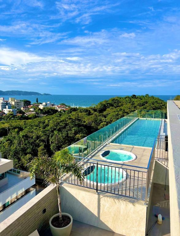 a swimming pool on a balcony with the ocean in the background at Promoção em Bombinhas até 4 pessoas c Piscina Aquecida in Bombinhas