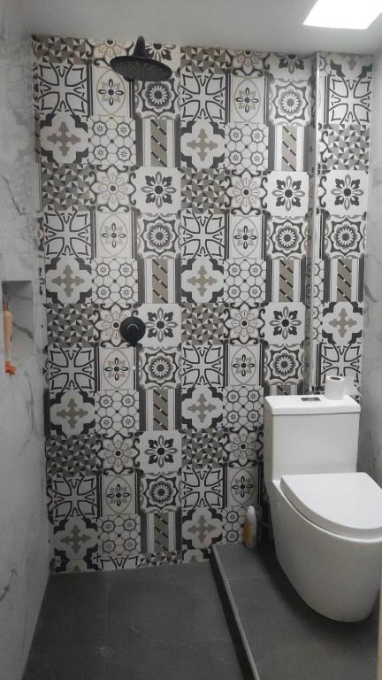 a bathroom with a toilet and a black and white tile wall at Departamento para PERUMIN AREQUIPA in La Apacheta