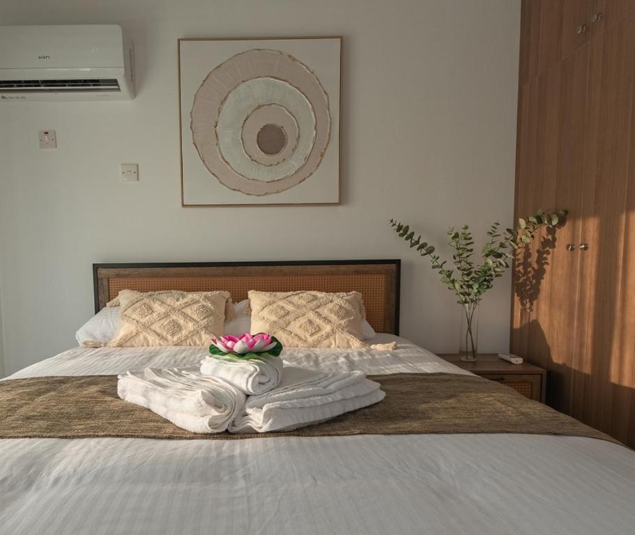 a bed with towels and a bowl of flowers on it at TelMar Sunset View 3 bed Apt - Duplex in Livadhia