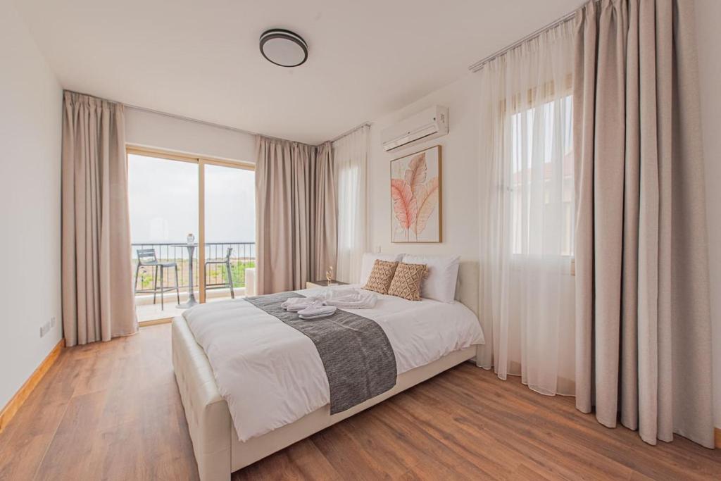 Un dormitorio con una cama y una ventana grande. en TelMar Royal Villa, en Mazotos