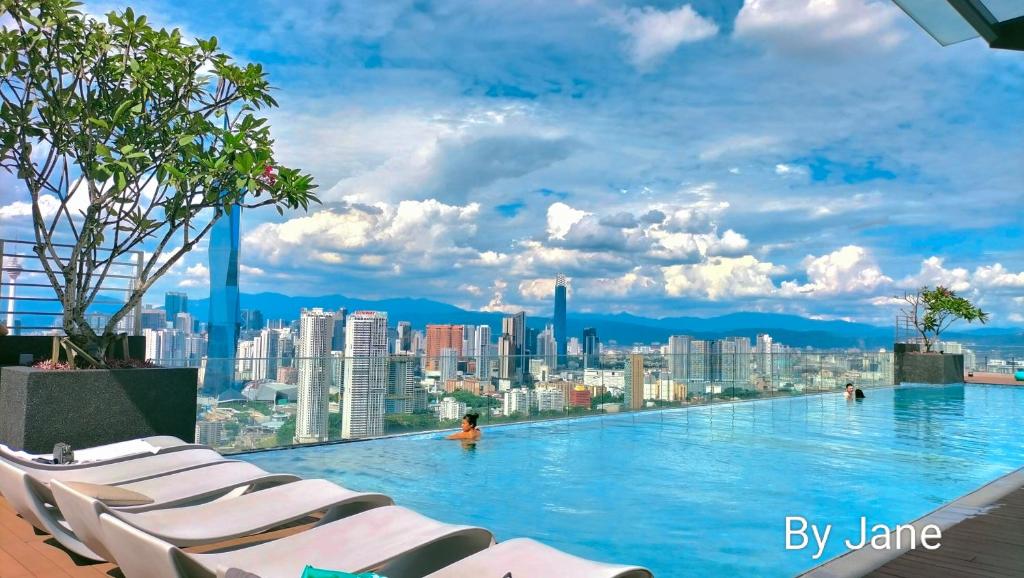 a swimming pool with chairs and a city skyline at Riveria City at KL Sentral by KKT in Kuala Lumpur