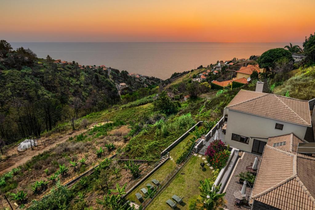 an aerial view of a house on a hill next to the ocean at Meerblick - 3-Bett Villa mit Terrassen & Hot-Tub in Fajã da Ovelha