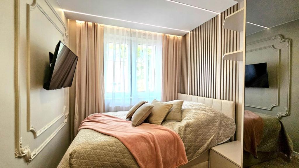 a small bedroom with a bed and a window at Centrum Comfort Rooms in Iława
