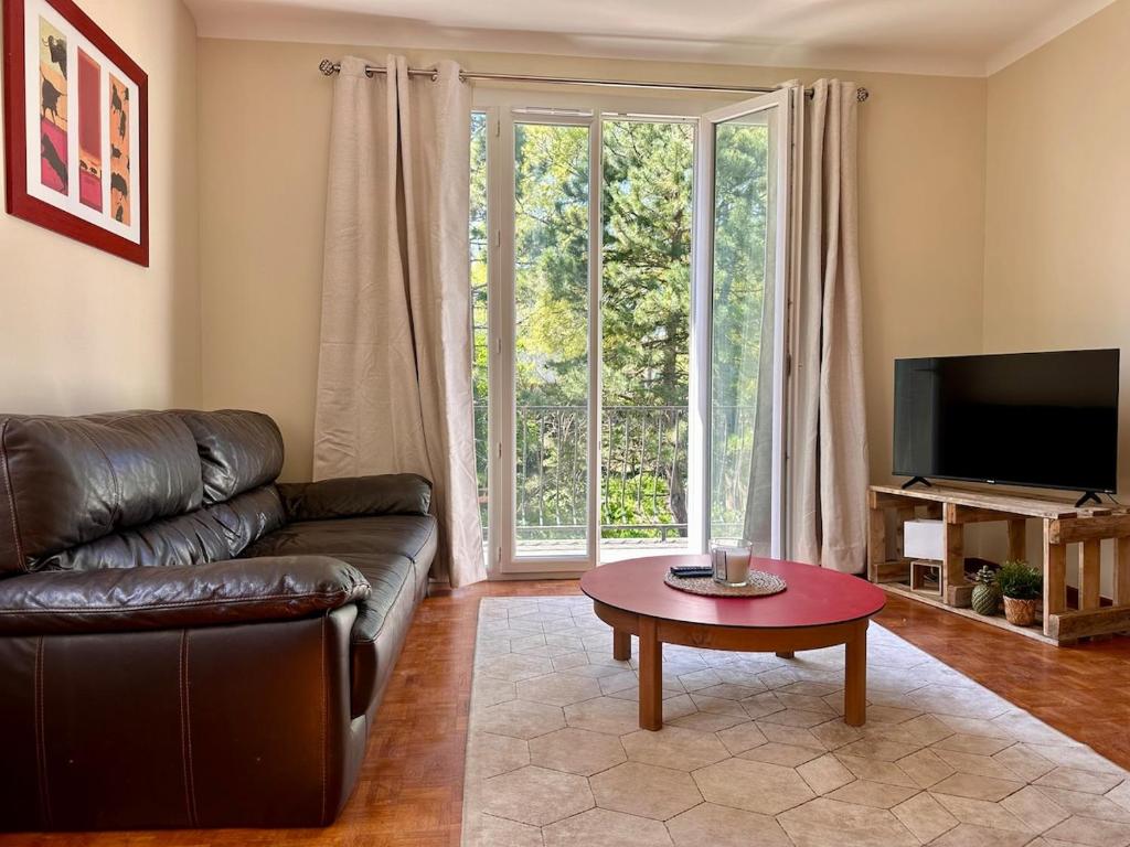 Una sala de estar con un sofá de cuero y una mesa de café. en Cozy apartment, en Châteauneuf-du-Rhône