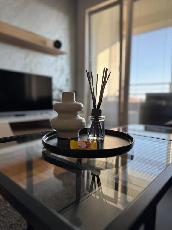 a glass coffee table with a vase and sticks on it at SUNRAY Apartman Požarevac in Požarevac