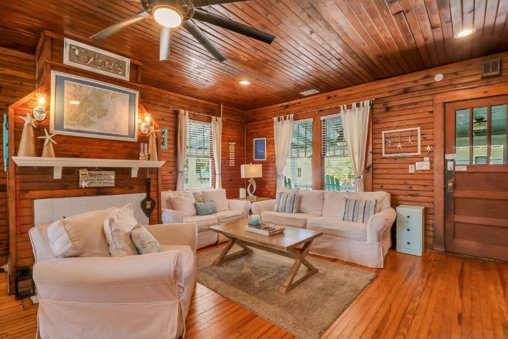 a living room with white furniture and wooden walls at Wish Upon a Big Starfish by Tybee Cottages in Tybee Island