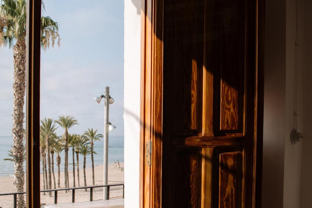 a door looking out at a beach with palm trees at Esquerdo 22 by Seaward Suites in Villajoyosa